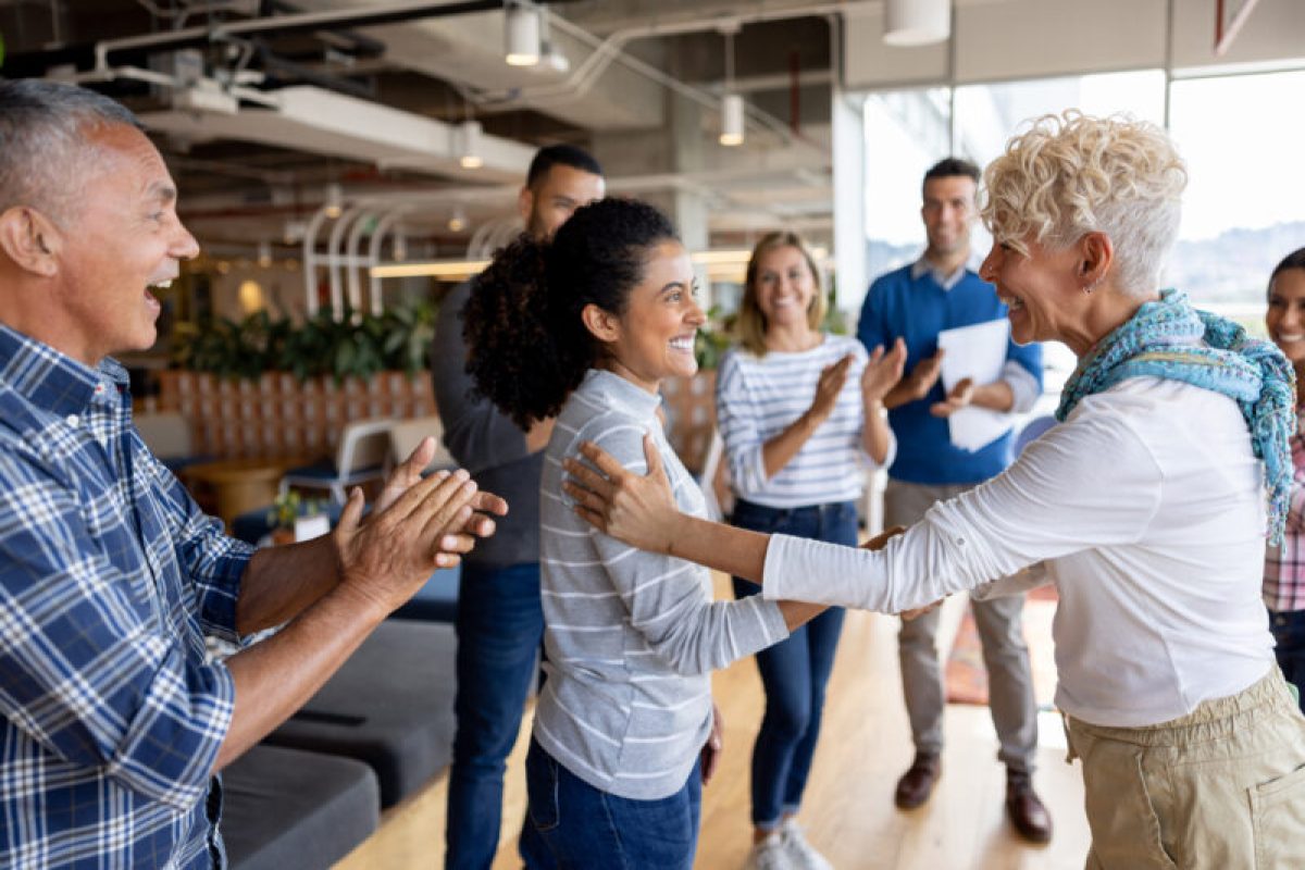 Boss giving woman a promotion at the office and team clapping for her Boss giving woman a promotion at the office and team clapping for her in a business meeting