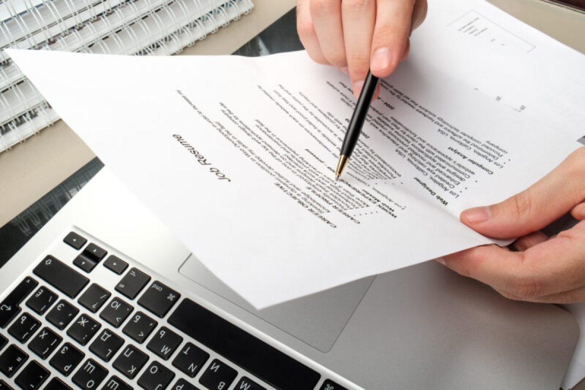 Working in a home office Adult man holding paperwork with table in home office with laptop