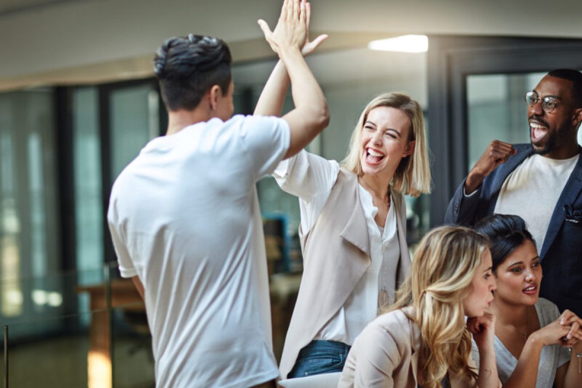 We’ve done it again! Shot of a group of colleagues giving each other a high five while using a computer together at work