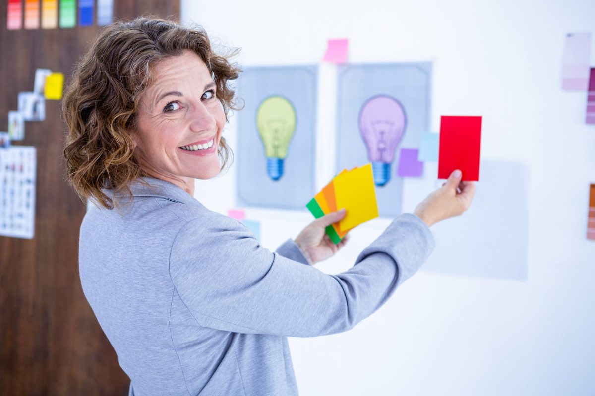 Creative businesswoman holding color cards and looking at camera in office