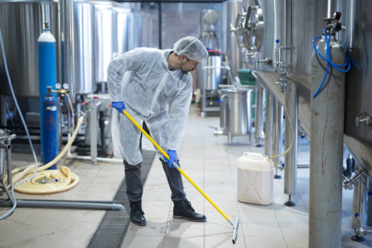 Professional industrial cleaner in protective uniform cleaning floor of food processing plant. Cleaning services. Professional industrial cleaner in protective uniform cleaning floor of food processing plant. Cleaning services.