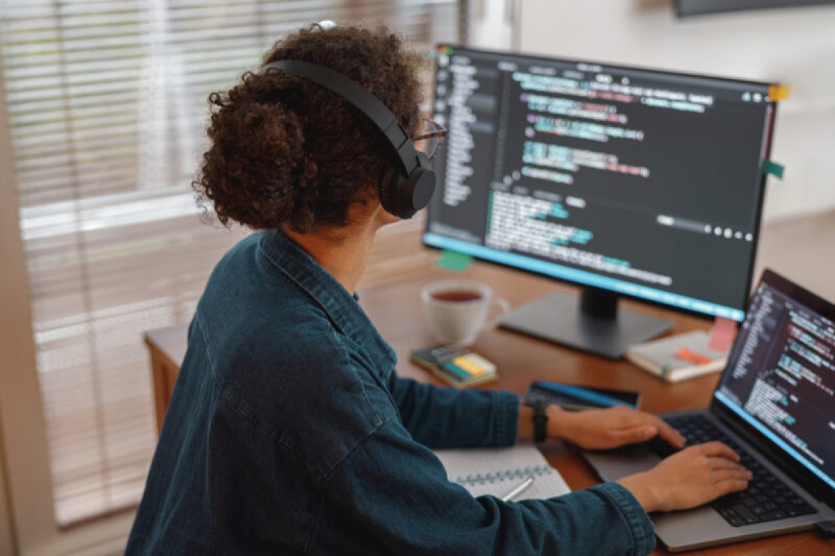 Woman in headphones freelance data scientist work remotely at home. Back view