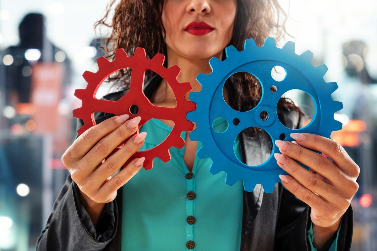 Businesswoman tries to work with gears system. Concept of teamwork and partnership