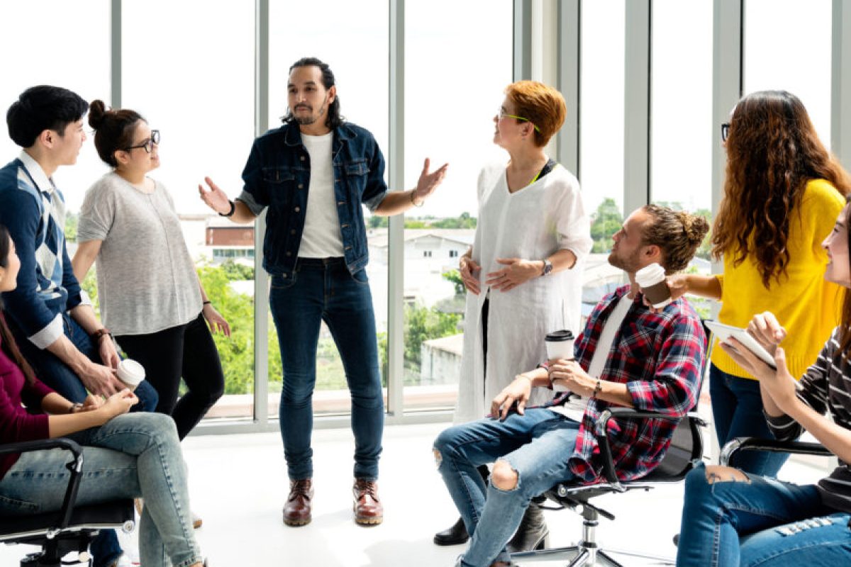 Attractive young multiethnic group talking at relax zone in coffee break time at office. Young asian hipster man sharing lifestyle idea to staff friends with fun and happy in happy workplace concept. Attractive young multiethnic group talking at relax zone in coffee break time at office. Young asian hipster man sharing lifestyle idea to staff friends with fun and happy in happy workplace concept.