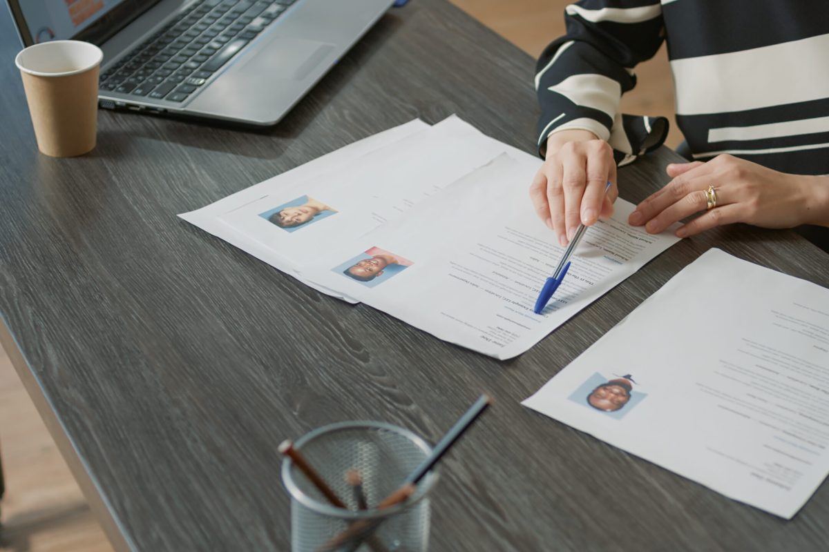 Office worker analyzing candidates cv and application form Office worker analyzing candidates cv and application form before attending job interview and hiring people. Recruiter searching on papers for person with business expertise. Close up.